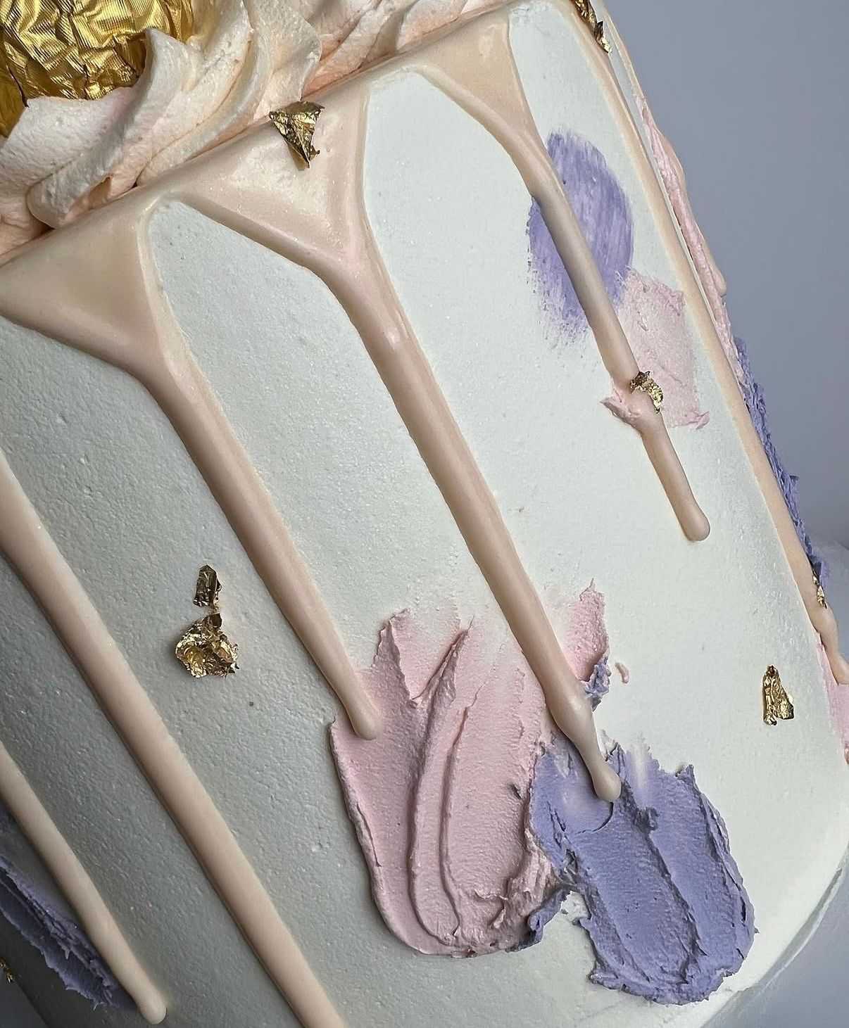 Pastel drip cake with pink and lavender buttercream and gold leaf